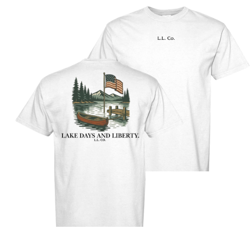 White t-shirt with a graphic of a lake, canoe, and American flag, featuring text 'Lake Days and Liberty, L.L. Co.'