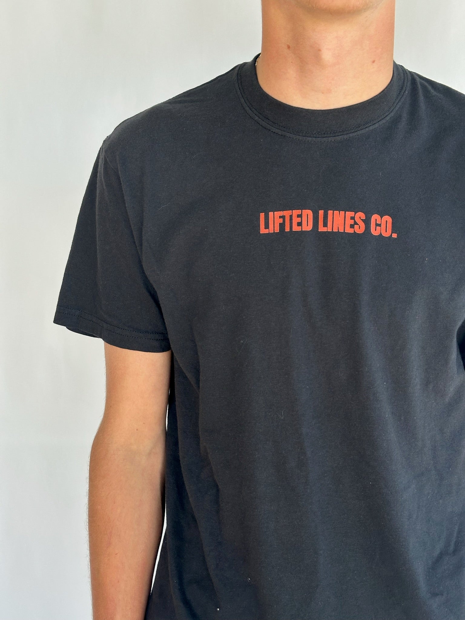 Person wearing a black t-shirt with 'Lifted Lines Co.' text in red on a plain background