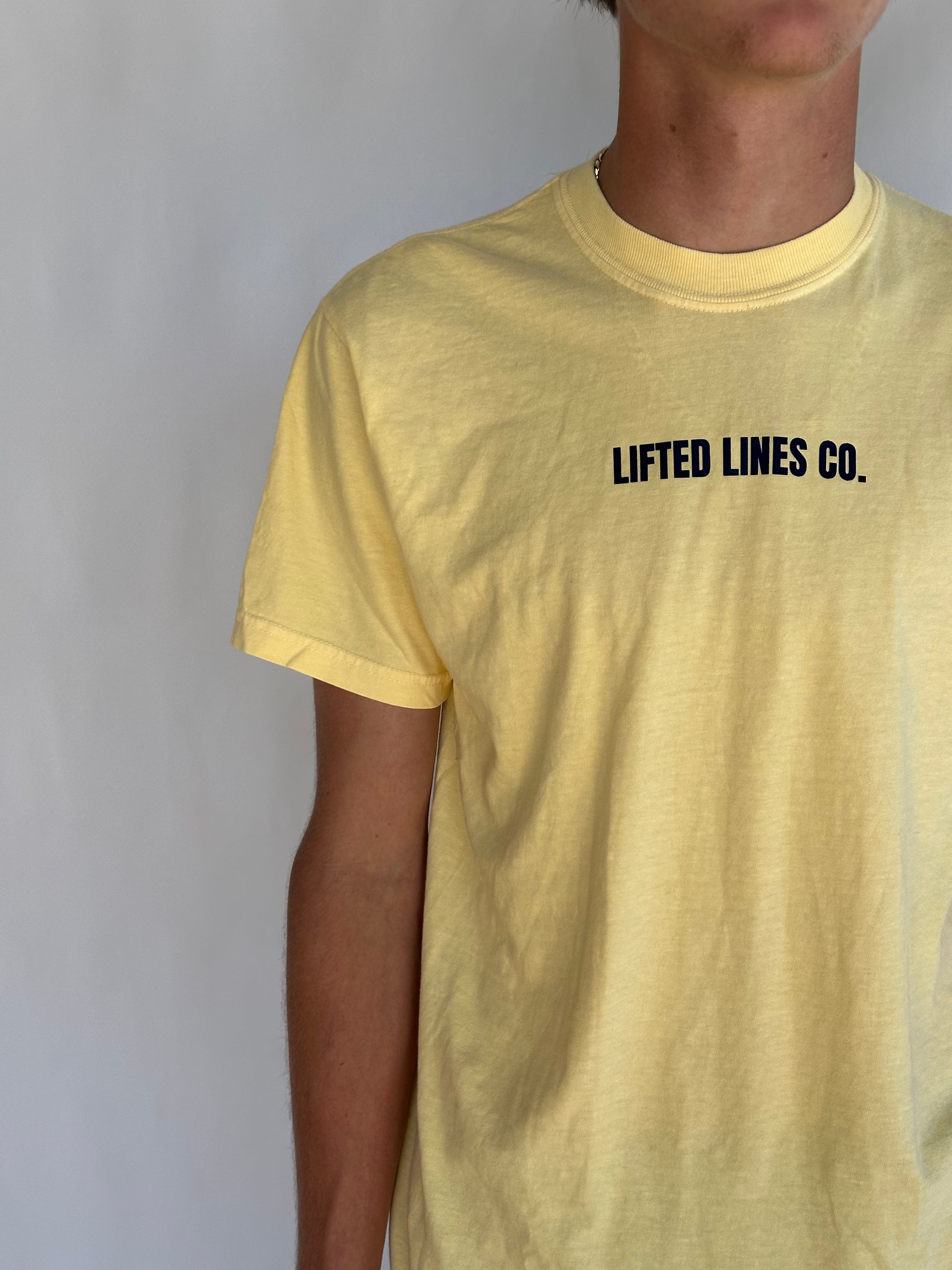 Yellow t-shirt with 'Lifted Lines Co.' text on a plain background
